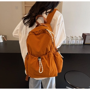 Vue arrière d'un mannequin portant un grand sac à dos orange avec poches à cordon