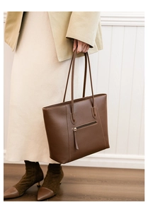 Detailed view of brown leather tote bag showing exterior zipper and stitching quality