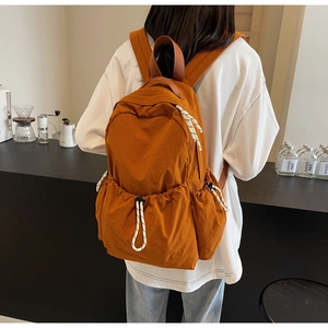 Détail du sac à dos de voyage en nylon orange-brun avec poches à cordon et cordons tressés