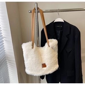 Detail of white faux fur tote bag with brown leather straps and square logo patch
