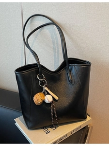Minimalist black PU leather tote bag with unique baseball pendants on stacked books