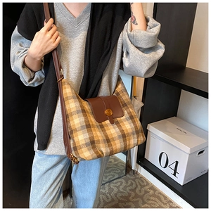 Détail du sac hobo à carreaux avec rabat en cuir marron et boucle dorée élégante