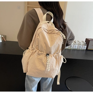 Détail d'un sac à dos de voyage en nylon beige clair avec poches à cordon et texture