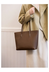 Detail of dark brown tote bag with lychee texture and long shoulder straps for daily use