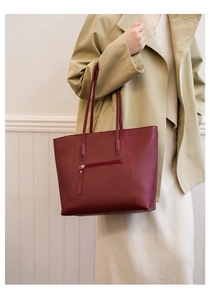 Close-up of wine red leather tote bag showing the back zipper pocket and slim straps