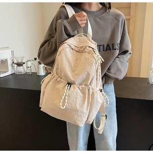 Détail du sac à dos en nylon beige avec poches latérales à cordon et fermeture éclair