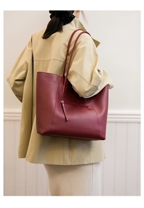 Detail of burgundy tote bag with back zipper pocket worn with a khaki coat