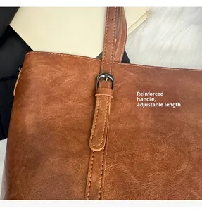 Détail de la poignée renforcée et de la boucle réglable sur le sac cabas en cuir marron