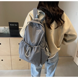 Détail du sac à dos en nylon gris foncé avec poche latérale à cordon et larges bretelles