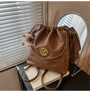 Detailed shot of brown leather bucket bag with gold chain and plush doll pendant charm