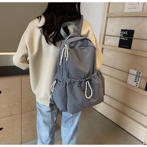 Détail du sac à dos en nylon gris-bleu avec poches latérales à cordon et fermeture éclair