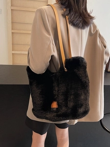 Minimalist black faux fur tote bag with brown leather straps shown on a model's shoulder