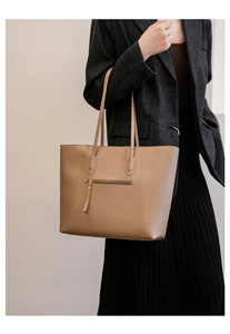 Detail of a large khaki tote bag with zipper tassel, styled for women's daily commute