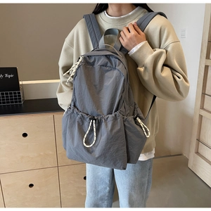 Détail du sac à dos de voyage en nylon gris avec poches latérales et tirettes tressées