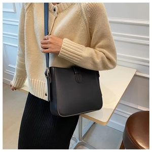 Nahaufnahme einer schwarzen matten Leder-Eimertasche, getragen von einem Model in Innenräumen