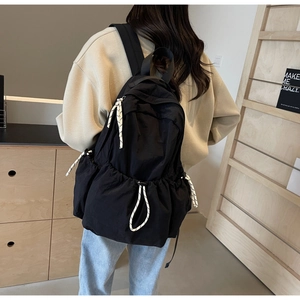 Détail d'un sac à dos léger en nylon noir avec cordons de serrage tissés noir et blanc