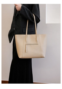 Detail of minimalist beige tote bag with front zipper pocket on a wool blazer outfit