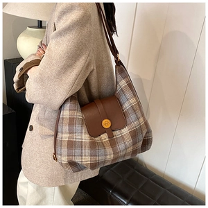 Détail du sac à carreaux d'automne avec rabat en cuir brun et boucle dorée en N