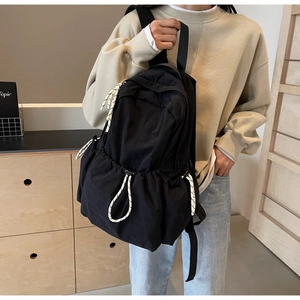 Détail du sac à dos de voyage en nylon noir avec cordon de serrage sur un modèle décontracté