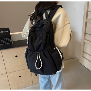Vue latérale du sac à dos en nylon noir avec cordes contrastées et bretelles larges