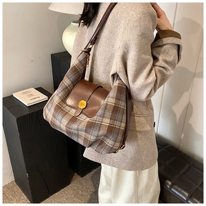Gros plan du sac hobo vintage à carreaux avec bandoulière en cuir et boucle dorée
