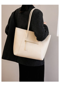 Detail view of the back zipper pocket on a large cream faux leather tote bag