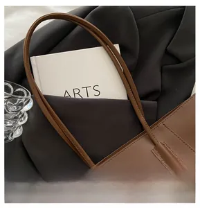 Detail of dark brown tote bag on a black blazer with office essentials for work