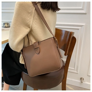 Detailansicht einer braunen Bucket Bag aus Leder, getragen mit stilvollem Strickoutfit
