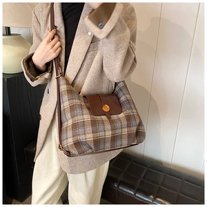 Détail du sac à carreaux vintage avec rabat en cuir marron et boucle dorée en N