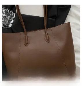 Detail of a deep brown faux leather tote bag with elegant vertical stitching details