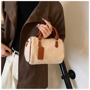 Detailed close-up of plush off-white Boston bag with brown leather trim and golden hardware