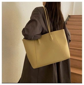 Detailed back view of a large ginger yellow leather tote bag worn over a dark winter coat