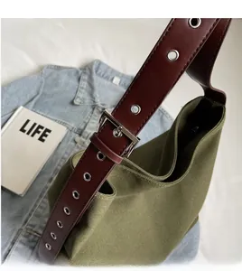 Detail of adjustable long shoulder strap with metal eyelets on green canvas tote bag