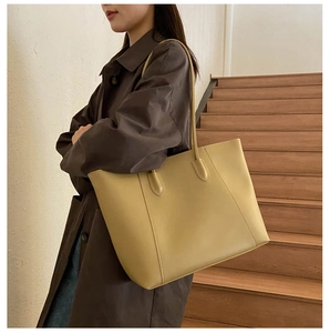 Detail shot of mustard yellow faux leather tote bag with long shoulder straps on a model