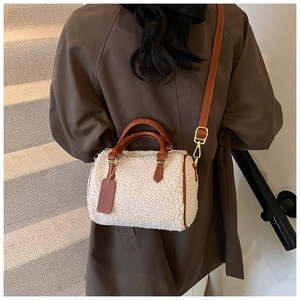 Detail of plush off-white Boston bag with brown leather trim and golden metal hardware