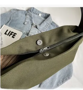Detail view of army green canvas bag featuring zipper closure and magnetic snap button