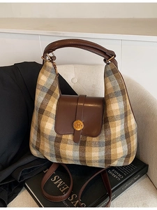 Sac hobo à carreaux avec poignées en cuir et boucle dorée M sur un canapé beige