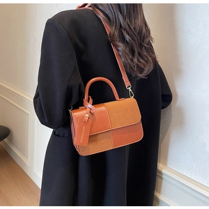Detalle de bolso bandolera de retazos marrones con asa y accesorios dorados