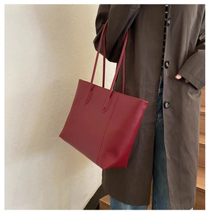 Dark red tote bag shown on model with dual slim shoulder straps for daily commuting