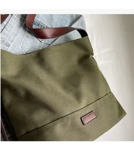 Detailed texture of army green canvas tote bag with brown leather straps and soft fabric