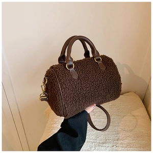 Close-up of soft brown faux shearling Boston bag with leather handles and gold hardware