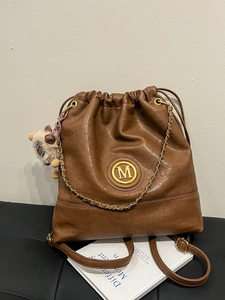 Brown leather drawstring bucket backpack with gold M logo and cute alpaca charm pendant