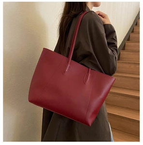 Detail of burgundy tote bag showing matte leather texture and elegant shoulder drape
