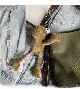 Brown-green plush frog charm with metal chain on canvas bag and denim jacket