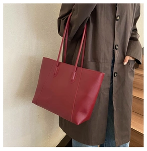 Red large capacity tote bag shown on model with long shoulder straps for daily commute