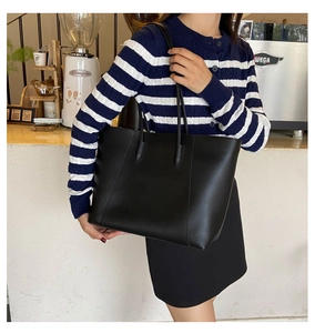 Asian model wearing a black minimalist matte leather tote bag in a sunlit cafe setting