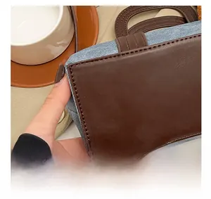 Detailed close-up of blue denim and brown leather bucket bag with precise stitching