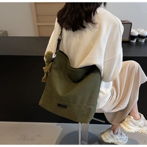 Olive green canvas tote bag with adjustable strap and cute frog plush pendant accessory