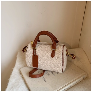 Detail of plush Boston bag featuring cream faux fur texture and brown leather handles