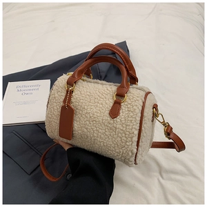 Detail of plush faux shearling textures and brown leather handles on the bucket bag